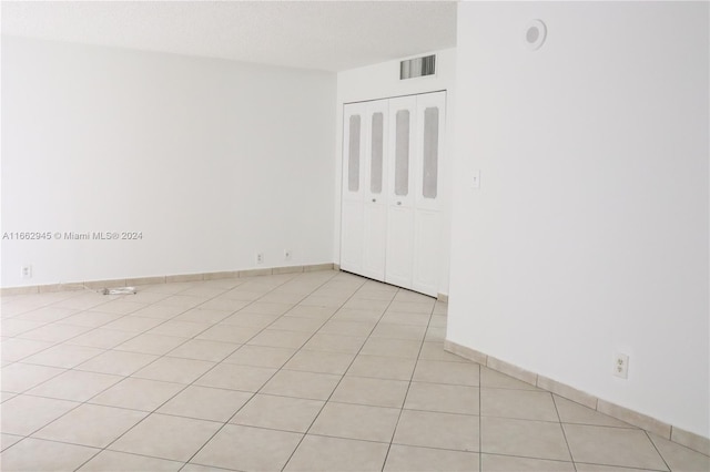 tiled empty room featuring a textured ceiling