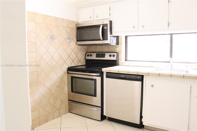 16919 N Bay Rd Unit 118, Sunny Isles Beach, FL 33160 - kitchen with stainless steel appliances, tile counters, white cabinetry, and light tile patterned flooring