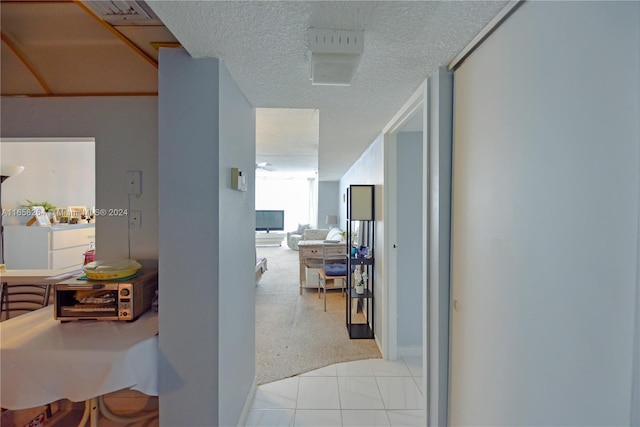 hall featuring light carpet, washer / clothes dryer, and a textured ceiling