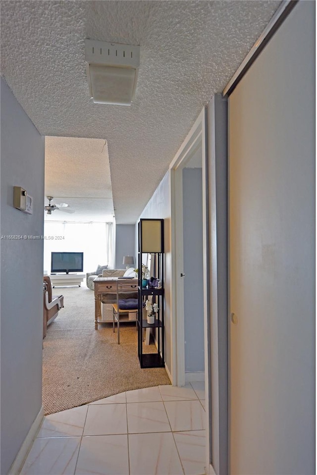 hall featuring a textured ceiling and light colored carpet