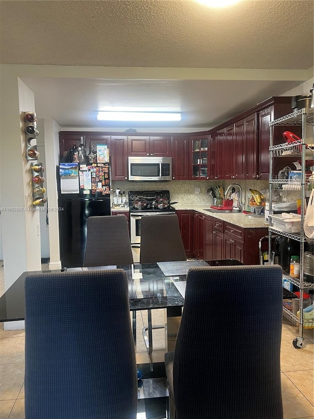 kitchen with light tile patterned flooring, appliances with stainless steel finishes, backsplash, and sink