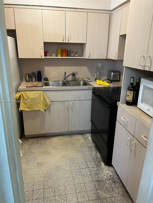 kitchen with black electric range oven, light brown cabinets, and sink