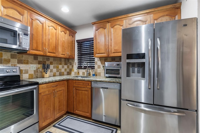 kitchen featuring light stone counters, appliances with stainless steel finishes, tasteful backsplash, and sink