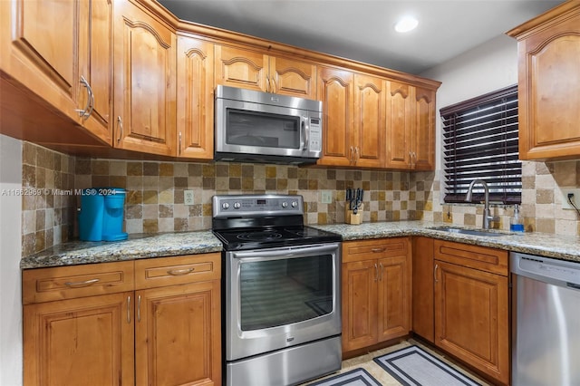 kitchen featuring light stone countertops, appliances with stainless steel finishes, sink, and tasteful backsplash