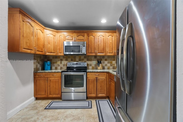 kitchen featuring light stone counters, appliances with stainless steel finishes, light tile patterned floors, and tasteful backsplash