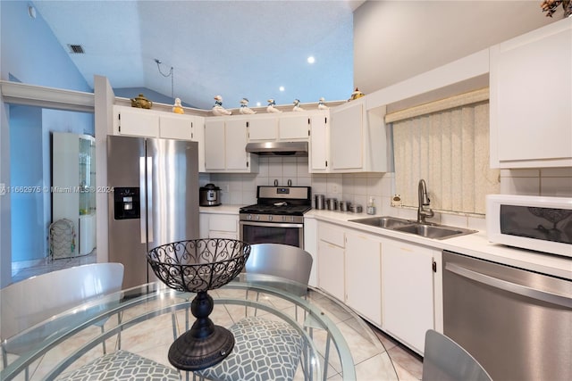 kitchen with white cabinets, lofted ceiling, sink, tasteful backsplash, and appliances with stainless steel finishes