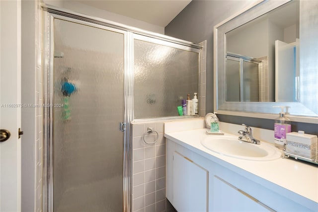 bathroom with vanity, tile walls, and a shower with shower door