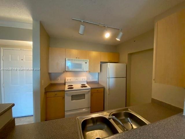 kitchen featuring light brown cabinetry, rail lighting, white appliances, and sink