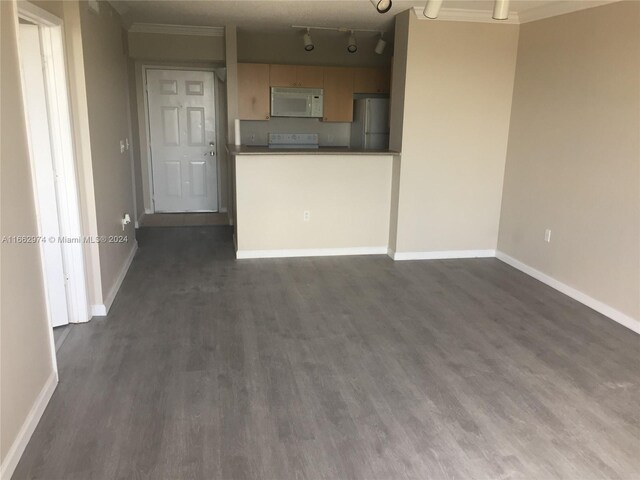 unfurnished living room featuring track lighting, ornamental molding, and dark wood-type flooring