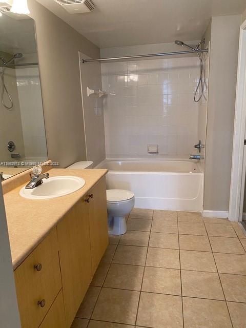 full bathroom featuring tiled shower / bath combo, vanity, toilet, and tile patterned floors