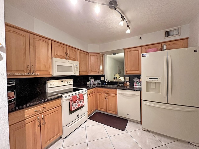 kitchen featuring rail lighting, light tile patterned flooring, backsplash, white appliances, and a textured ceiling