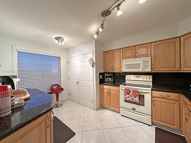 kitchen with rail lighting, white appliances, a textured ceiling, and backsplash