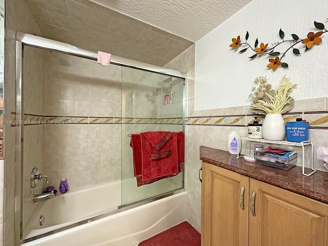 bathroom with vanity, tile walls, and combined bath / shower with glass door