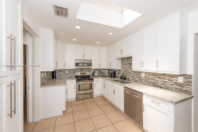 kitchen with light stone counters, sink, white cabinets, decorative backsplash, and stainless steel appliances