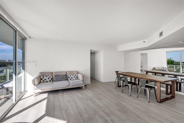 dining area with light wood-style floors, visible vents, and a wall of windows