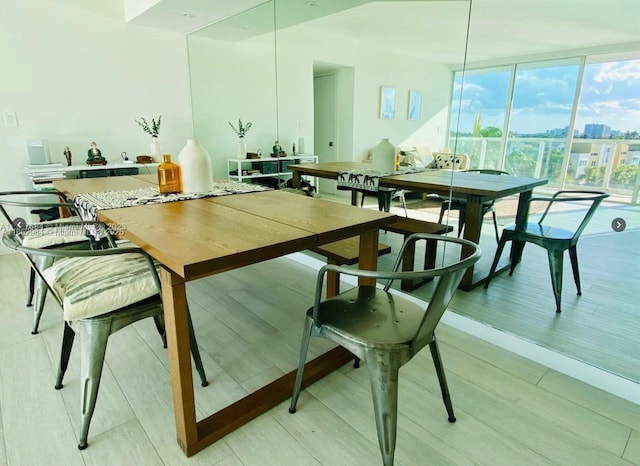 dining room featuring a view of city, light wood finished floors, and floor to ceiling windows