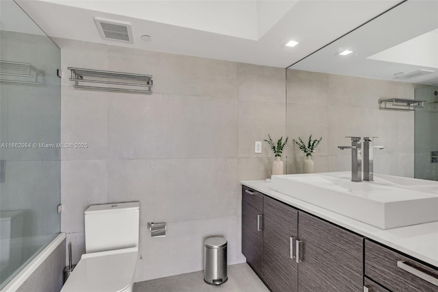 full bathroom with visible vents, tile walls, toilet, and vanity