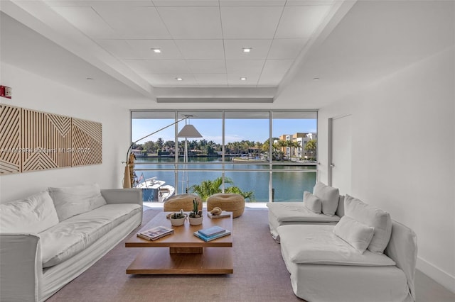 living area with a water view, expansive windows, a tray ceiling, and recessed lighting