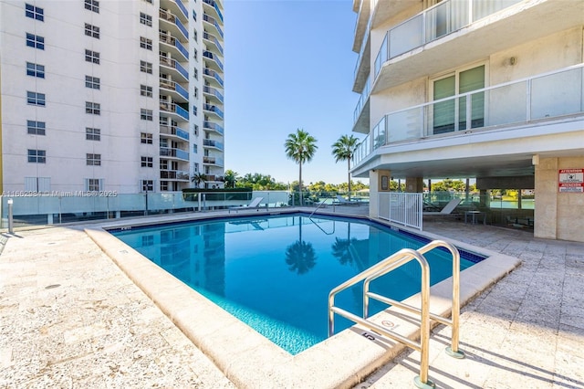 community pool with a patio and fence