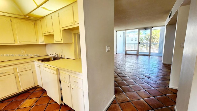 kitchen featuring dark tile patterned flooring, white dishwasher, a wall of windows, and sink