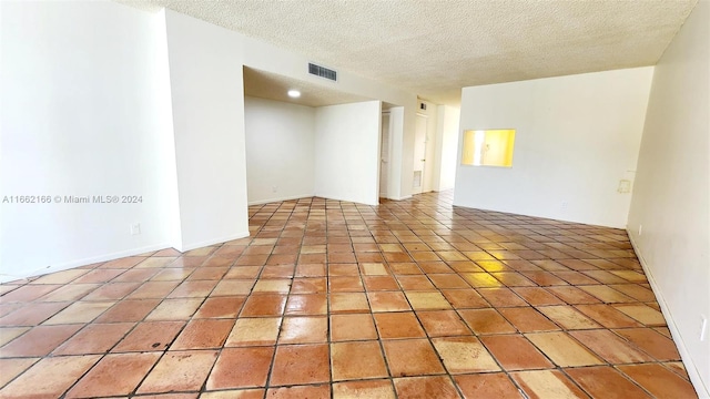 tiled empty room with a textured ceiling