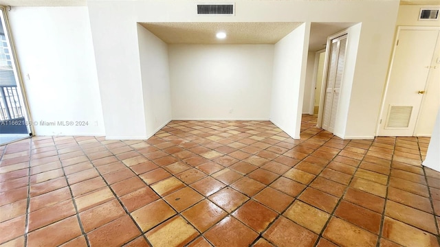 tiled empty room with a textured ceiling