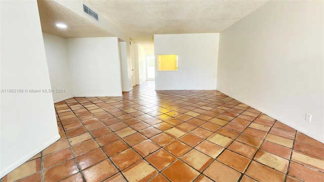 tiled empty room featuring a textured ceiling