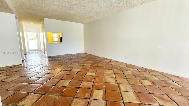 unfurnished room with a textured ceiling and tile patterned floors