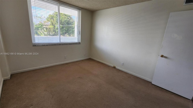 carpeted empty room with a textured ceiling