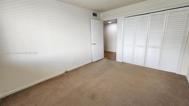 unfurnished bedroom with a textured ceiling, carpet, and a closet