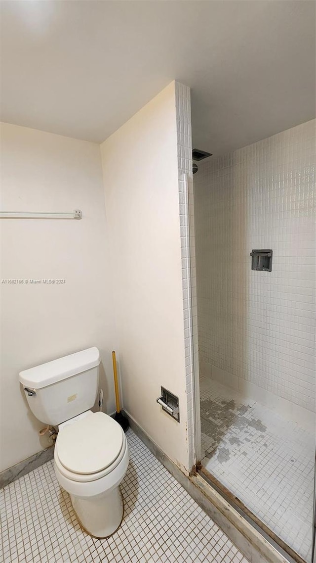 bathroom featuring a tile shower, tile patterned flooring, and toilet