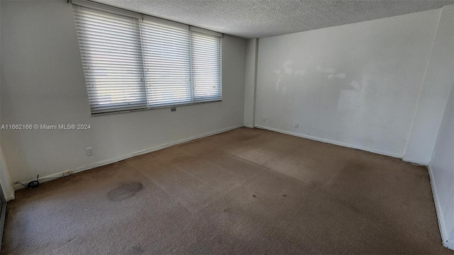 carpeted spare room featuring a textured ceiling