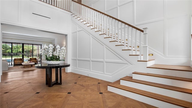 staircase with parquet floors and a high ceiling