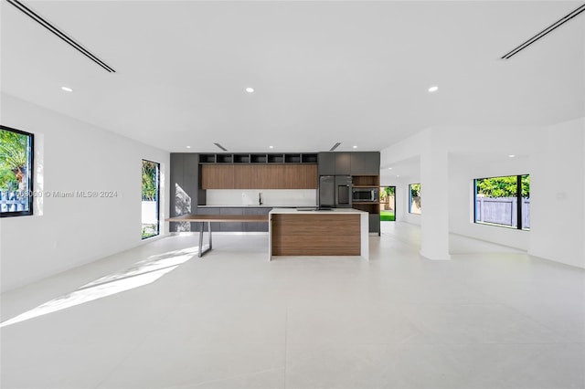 kitchen with a healthy amount of sunlight, stainless steel appliances, a kitchen island, and sink