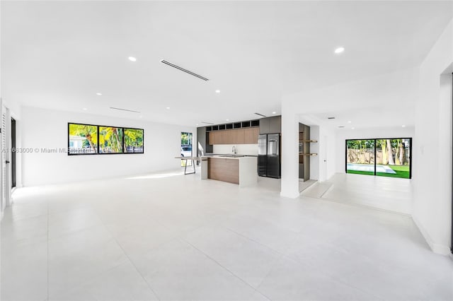 unfurnished living room featuring sink and a healthy amount of sunlight