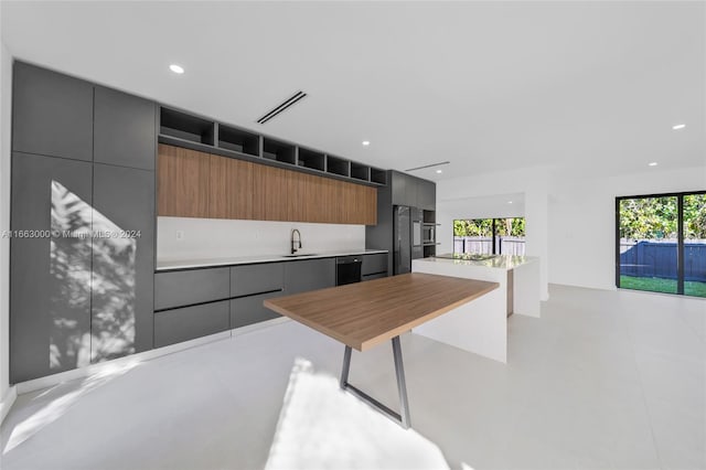 kitchen with stainless steel refrigerator, a breakfast bar area, sink, and a kitchen island