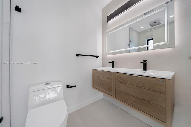 bathroom with concrete flooring, vanity, and toilet