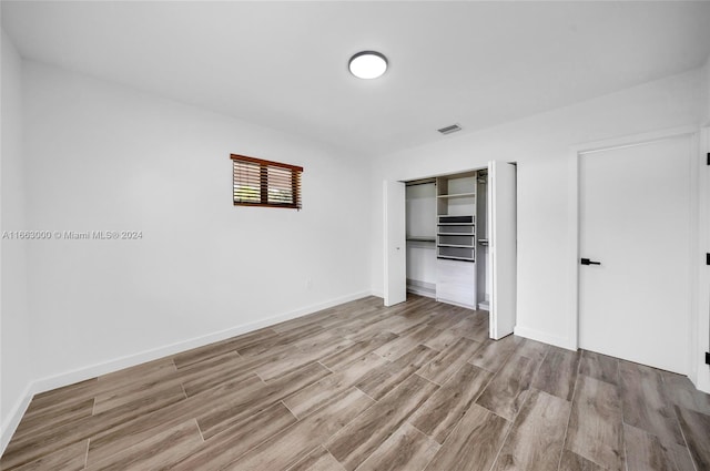 unfurnished bedroom featuring light hardwood / wood-style flooring and a closet