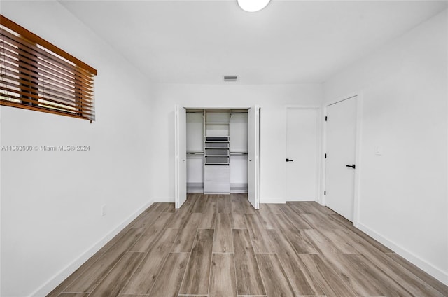 unfurnished bedroom with light wood-type flooring and a closet