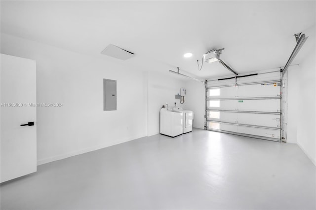 garage featuring washing machine and clothes dryer, a garage door opener, and electric panel