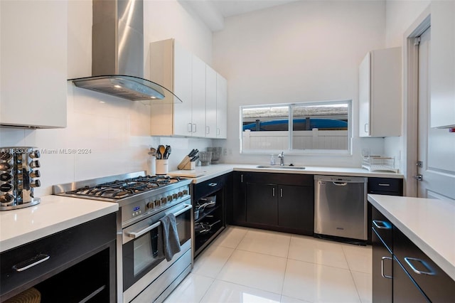2112 NE 17th Ave, Wilton Manors, FL 33305 - kitchen with wall chimney range hood, appliances with stainless steel finishes, a sink, light countertops, and dark cabinetry