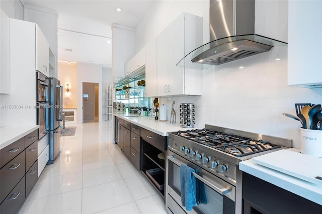 2112 NE 17th Ave, Wilton Manors, FL 33305 - kitchen featuring wall chimney range hood, white cabinets, appliances with stainless steel finishes, and light countertops