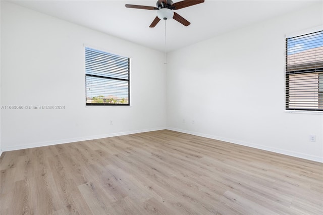 empty room featuring a wealth of natural light, ceiling fan, and light wood-type flooring