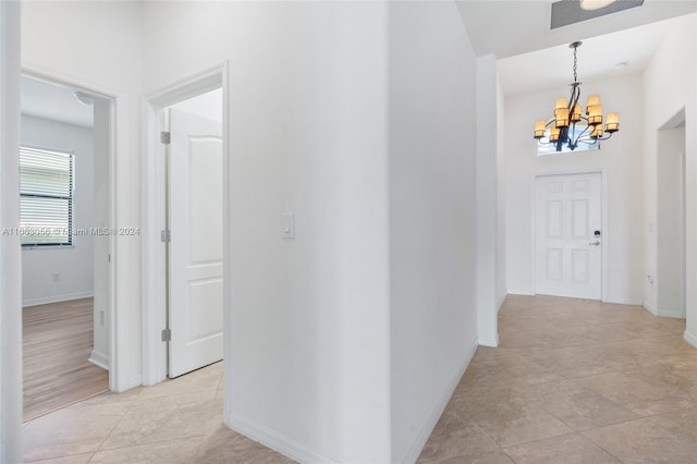 corridor featuring a notable chandelier and light tile patterned floors