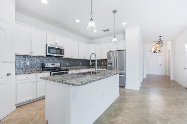 kitchen featuring hanging light fixtures, decorative backsplash, white cabinets, stainless steel appliances, and a kitchen island with sink