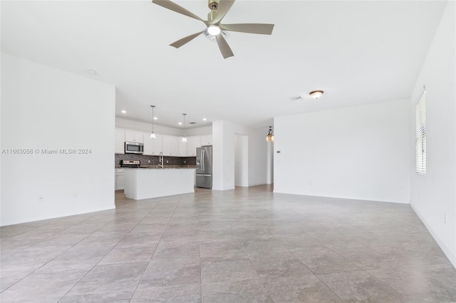 unfurnished living room featuring ceiling fan, light tile patterned floors, and sink