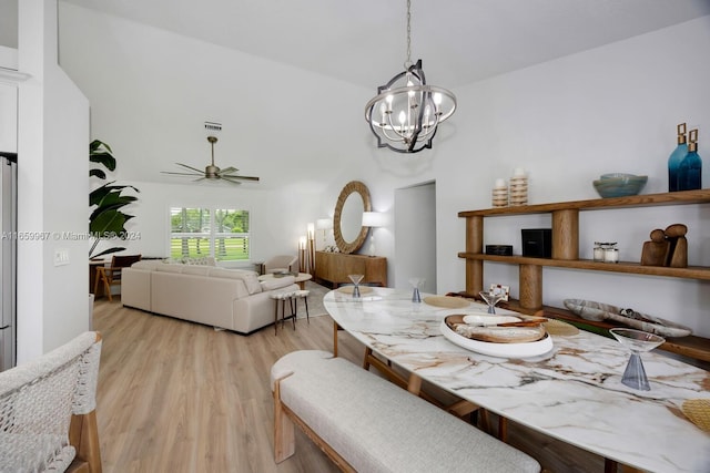 dining area featuring ceiling fan with notable chandelier, light hardwood / wood-style flooring, and vaulted ceiling