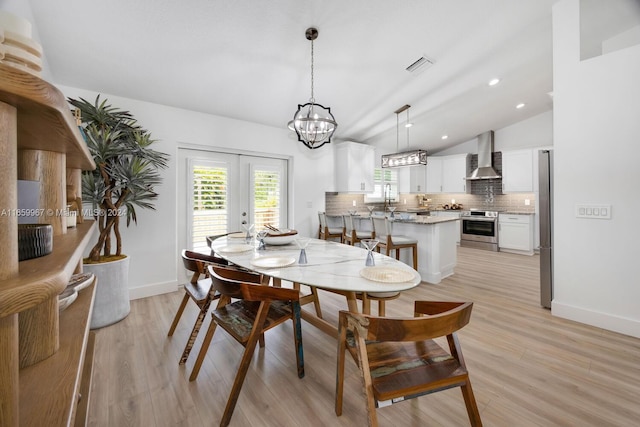 dining room featuring an inviting chandelier, light wood-type flooring, and lofted ceiling