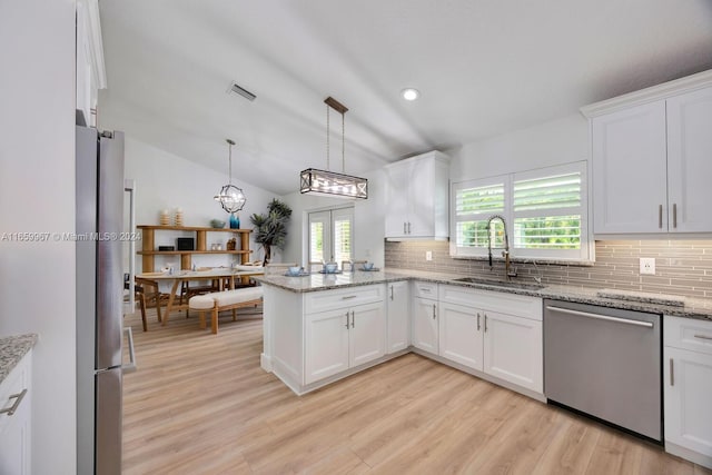 kitchen with kitchen peninsula, vaulted ceiling, stainless steel appliances, and white cabinetry