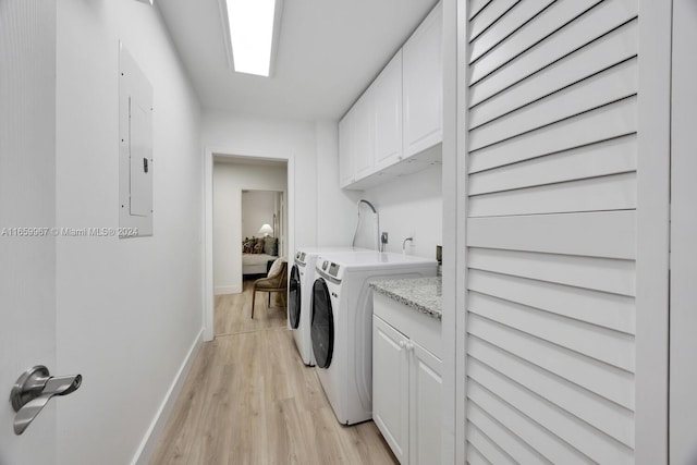 laundry area featuring cabinets, light wood-type flooring, electric panel, and washing machine and dryer